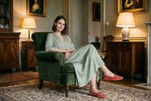 Modella seduta elegante con Friulane Babine in velluto salmone, outfit salvia, fatte a mano in Friuli – Le Babine