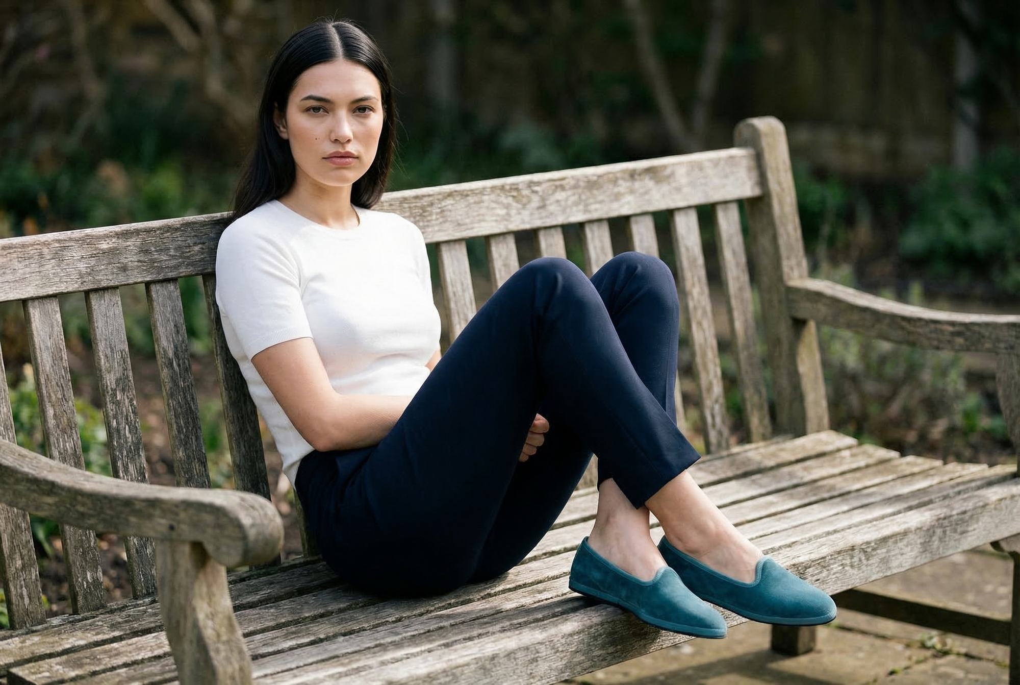 Modella seduta su panchina con Friulane Babine in velluto verde fiordo, outfit navy, fatte a mano in Friuli – Le Babine